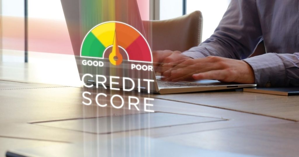 A person working on a laptop with a credit score gauge in the foreground, comparing the processes of credit repair vs credit restoration.