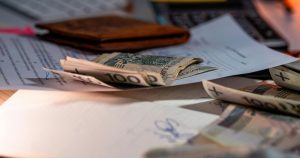 A close-up of cash and financial documents on a desk, including a statement with liens, representing financial management and debt resolution.