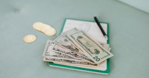 Cash and coins on a notebook, symbolizing financial planning and budgeting for paying off student loans.